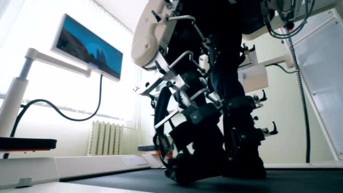 在步行练习中，将人的腿用训练机的键合起来。康复用电子医疗机器人。