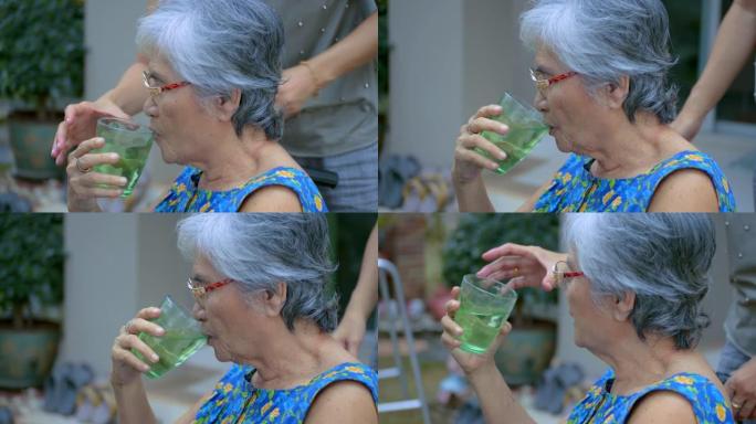 照顾者照顾老年妇女喝水。