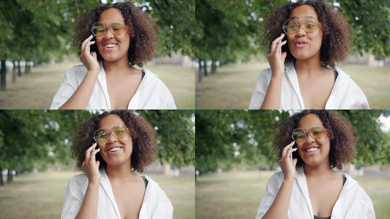 兴奋的非洲裔美国妇女在城市公园里用手机讲话