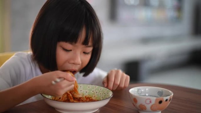 一个亚洲华人春天的年轻女孩在饭厅里家里用筷子吃意大利面