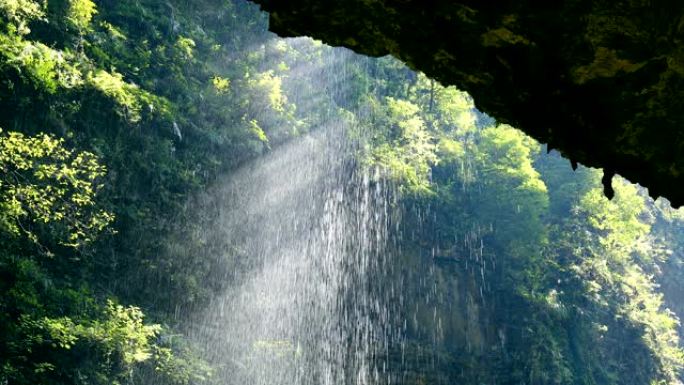 瀑布从山谷飞溅岩洞下雨天的阳光山涧