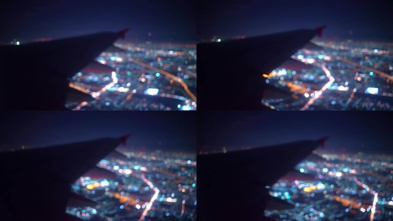 飞机机翼的散焦和夜间飞行的灯光城市照明