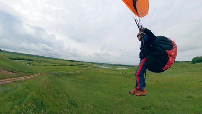 一名运动员驾驶滑翔伞飞越绿地。
