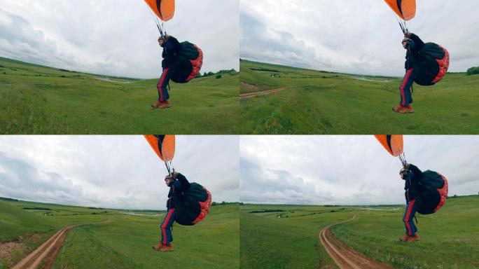 一名运动员驾驶滑翔伞飞越绿地。