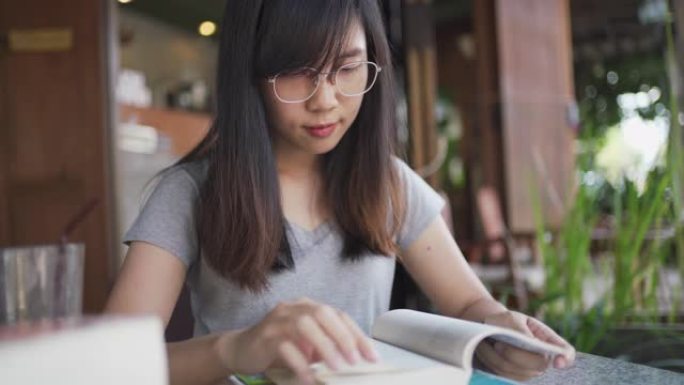 4k亚洲女性看书，在咖啡馆微笑和快乐放松