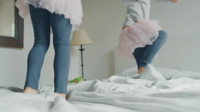 pigiama和pink tutu的两个小女孩姐妹在床上与枕头打架的真实照片