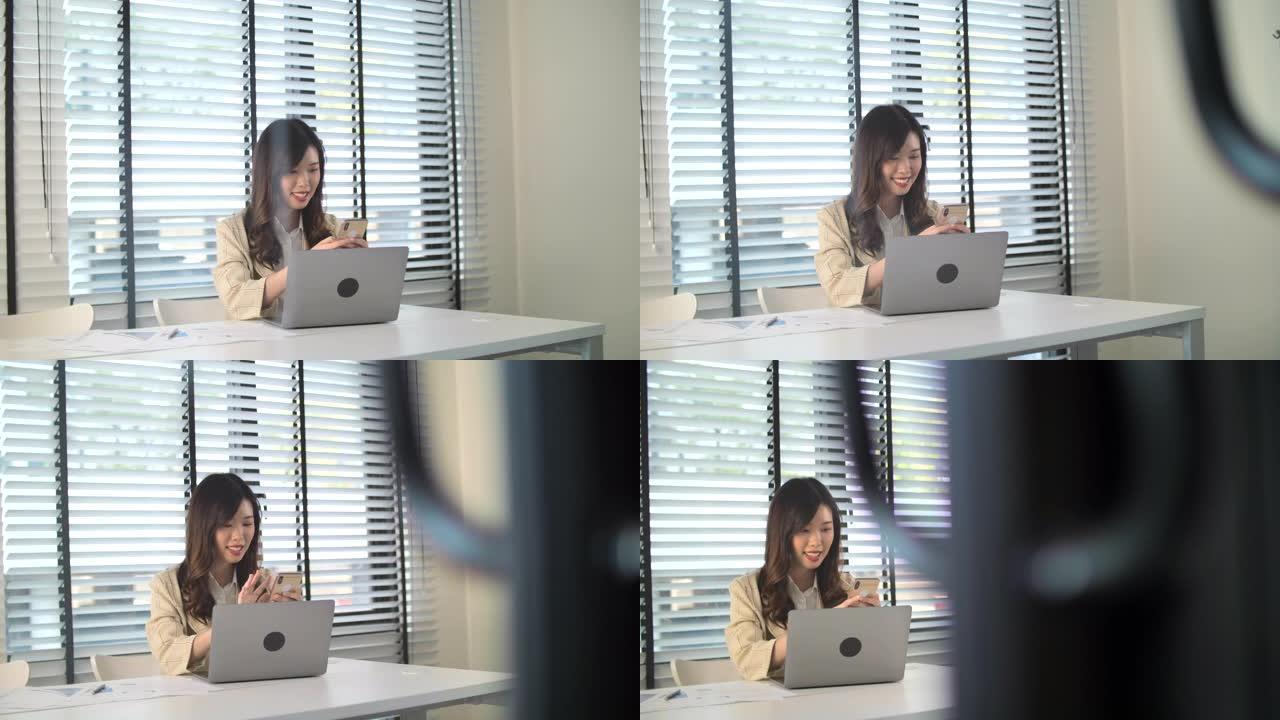 迷人的年轻亚洲女性在家工作，看着笔记本电脑