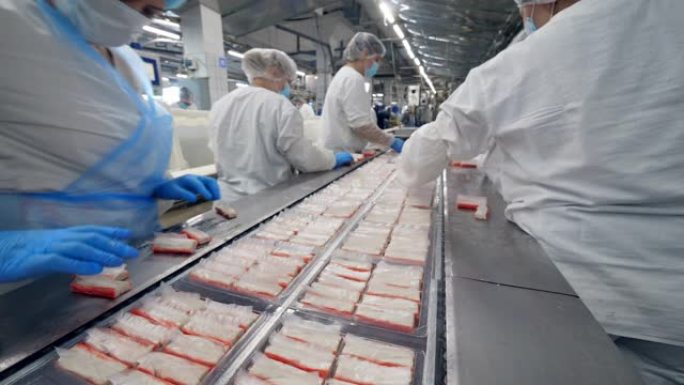 食品厂工人从移动生产线包装产品。