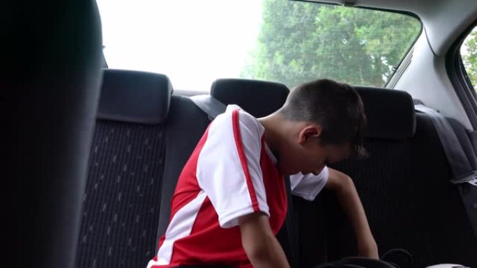 漂亮的小男孩在足球练习后上车并系上安全带