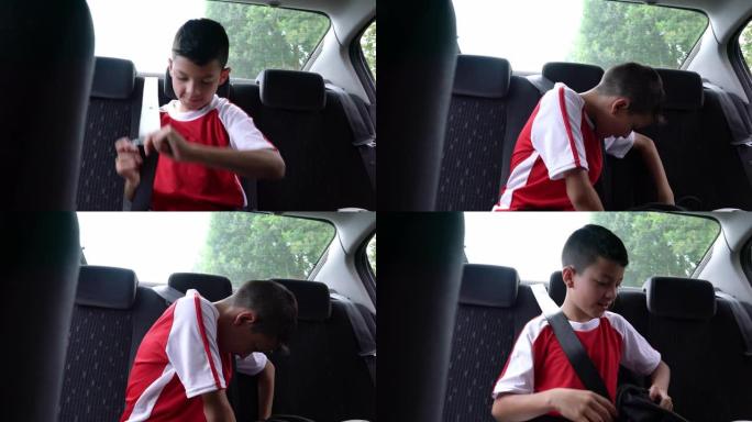 漂亮的小男孩在足球练习后上车并系上安全带