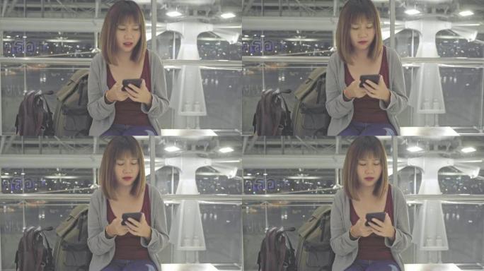 亚洲妇女坐在国际机场时使用智能手机。