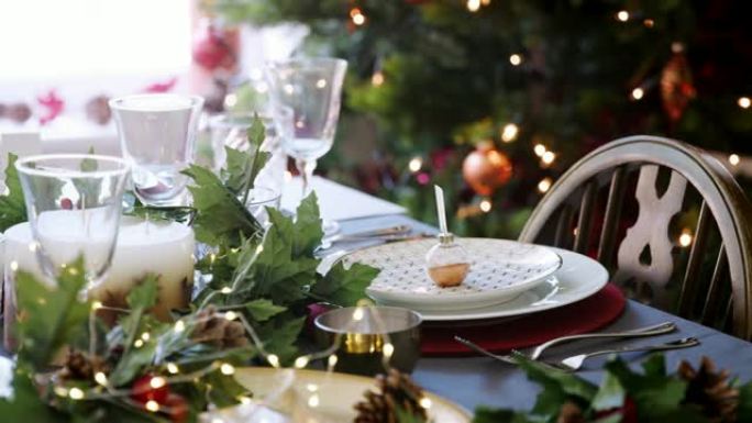 圣诞餐桌摆放摆设，摆设在盘子上，绿色和红色餐桌装饰，圣诞树和背景灯，特写