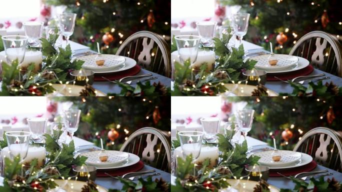 圣诞餐桌摆放摆设，摆设在盘子上，绿色和红色餐桌装饰，圣诞树和背景灯，特写