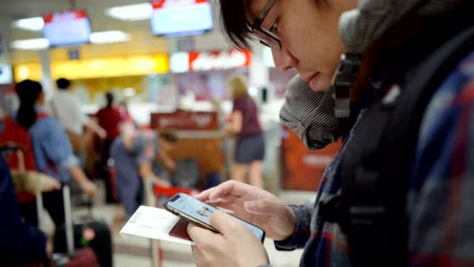 4k倾斜亚洲男子在机场值机柜台使用智能手机
