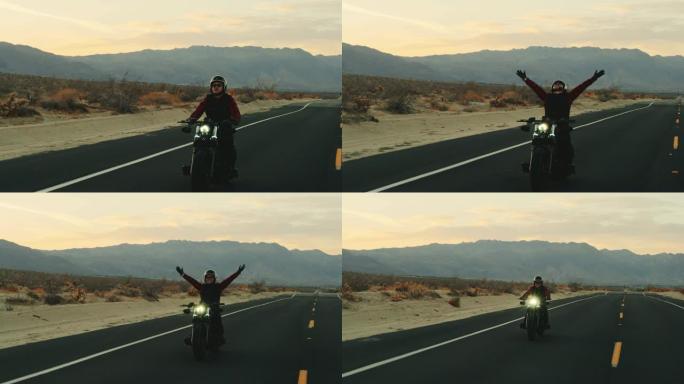 快乐的人在日落时骑着摩托车在空中举起手臂庆祝