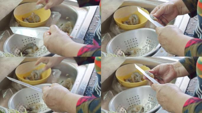 亚洲高级妻子在家里的厨房里为晚餐洗新鲜虾
