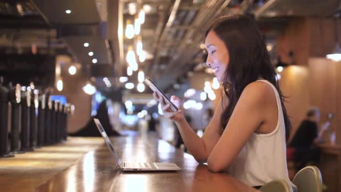 亚洲女性在咖啡馆使用智能手机进行社交媒体