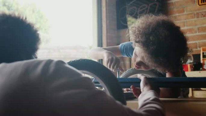 十几岁的男孩的特写镜头集中精力，俯身专注于与父亲一起建造赛车卡丁车时，他专心于拧紧螺栓，选择性专注