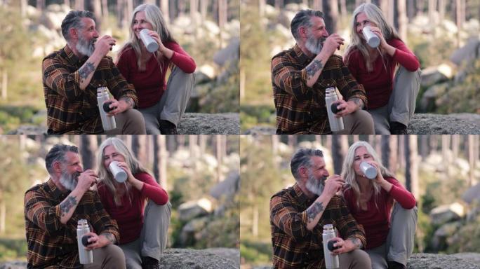在森林上喝热水瓶的高级夫妇的特写镜头