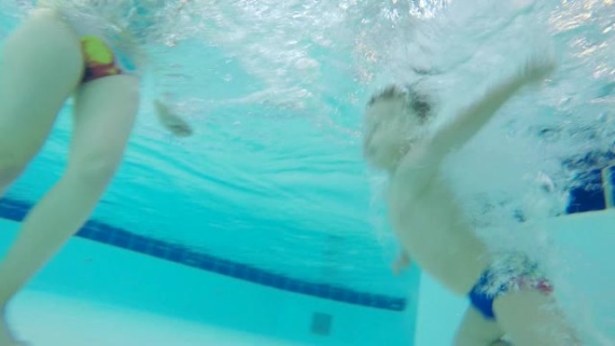 一个男孩在游泳池里潜水，学习在水下游泳，特写镜头。