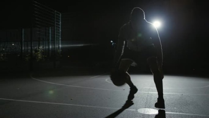 活跃的运动员在夜间运球篮球