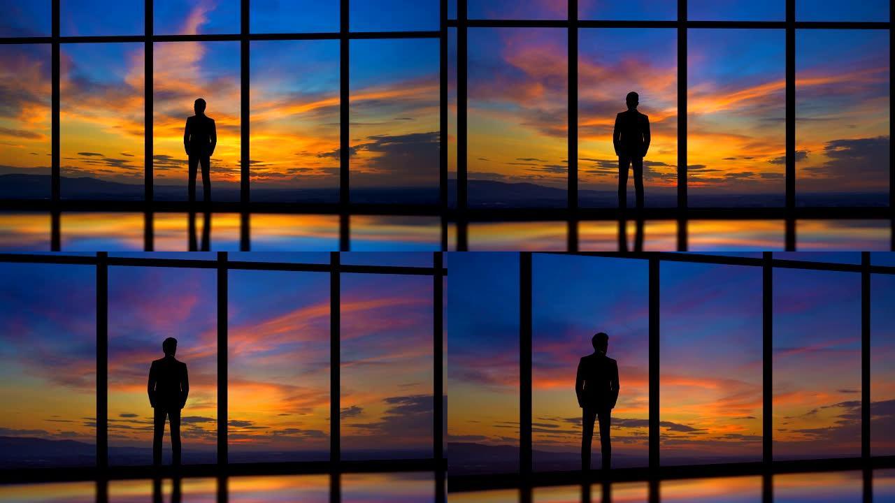 站在日落背景上靠近窗户的男性。时间流逝