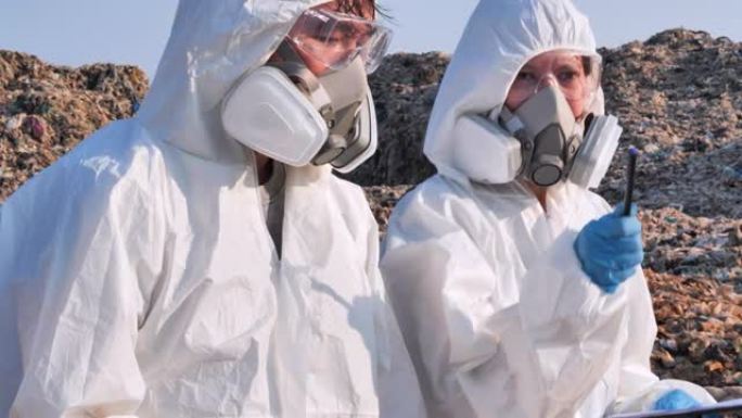 两名亚洲科学家穿着化学防护服病毒COVID-19.Biologists在废物中进行研究在电晕病毒调查