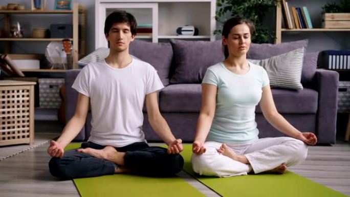 年轻的女孩和男孩在瑜伽后闭着眼睛放松荷花姿势