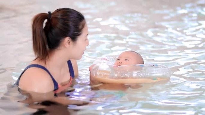 可爱的婴儿和他的母亲一起在游泳池里