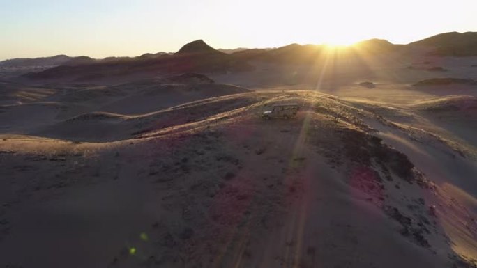 4x4野生动物园车辆的4k鸟瞰图，游客在纳米比亚纳米布沙漠的Hoanib山谷的山上观看日落