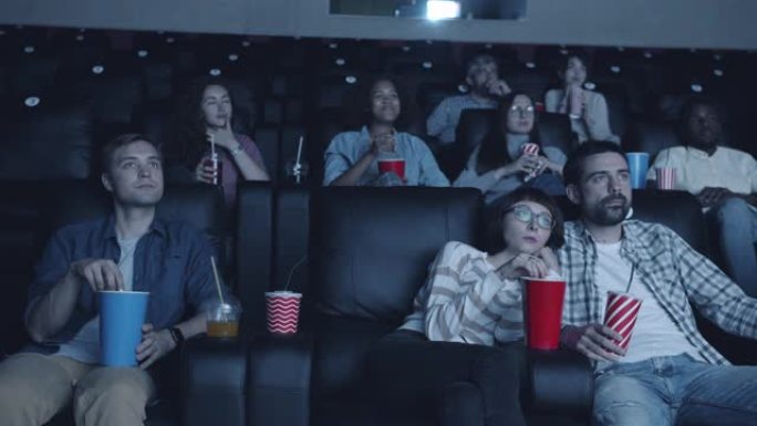 开朗的学生坐在黑暗的房间里在电影院欣赏有趣的电影