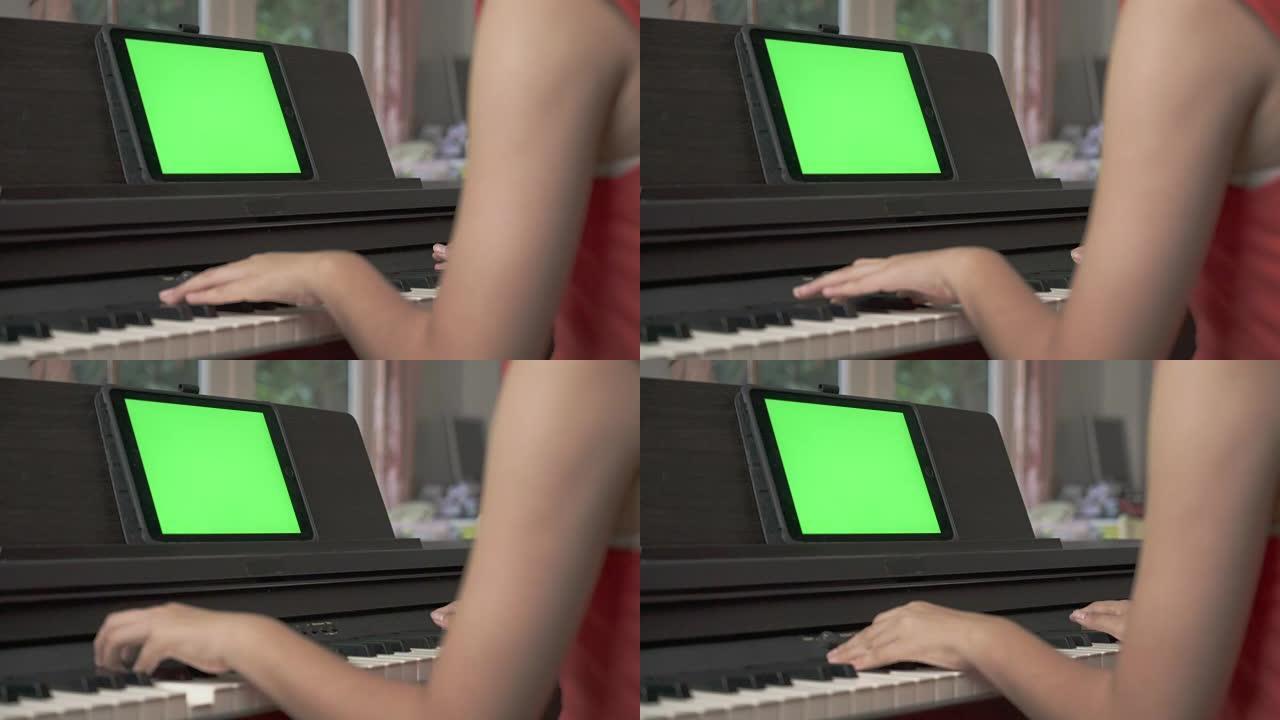 年轻的亚洲女孩在绿屏平板电脑上的钢琴在线课程上手工学习