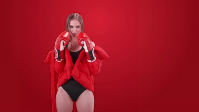 穿着拳击手套的诱人女人在红色背景下摆姿势