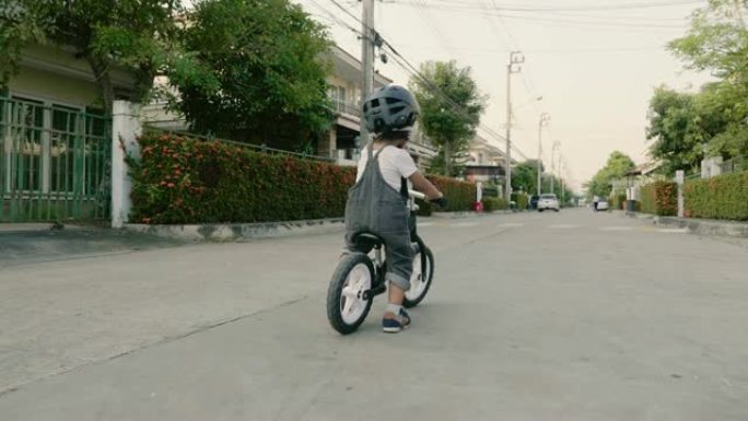 小而快乐的男孩在人行道上骑自行车