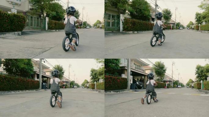 小而快乐的男孩在人行道上骑自行车