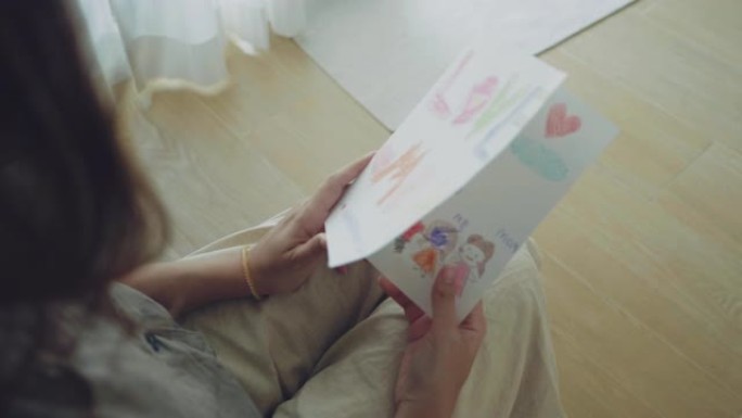 年轻女子和她的小女孩在家里看明信片。