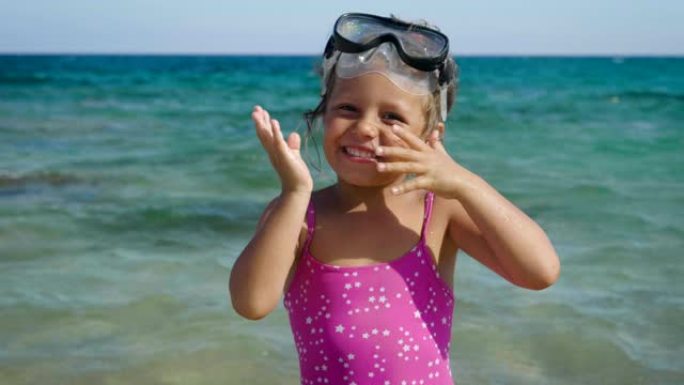 美丽的小女孩在海上玩耍，可爱的面具微笑游泳