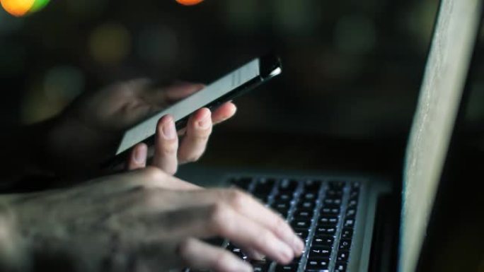 男人在晚上用笔记本电脑和手机工作