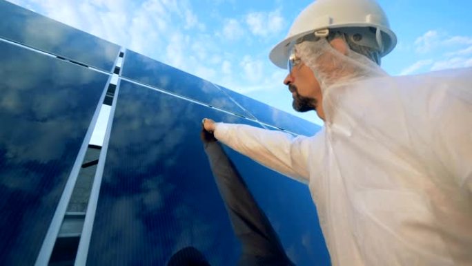 一名男子清理屋顶上的太阳能电池板，关闭。