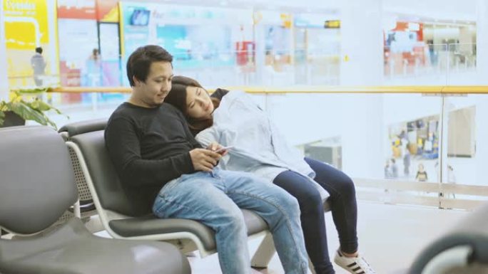 4k镜头场景有吸引力的夫妇亚洲旅客坐和睡觉，行李等候航班在机场航站楼，运输和旅客旅行概念