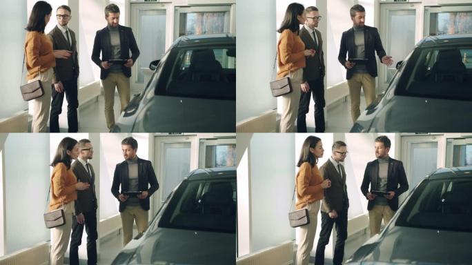 有吸引力的夫妇在豪华汽车经销店与自信的汽车销售经理交谈