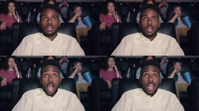 震惊的非裔美国人张开嘴在电影院看电影