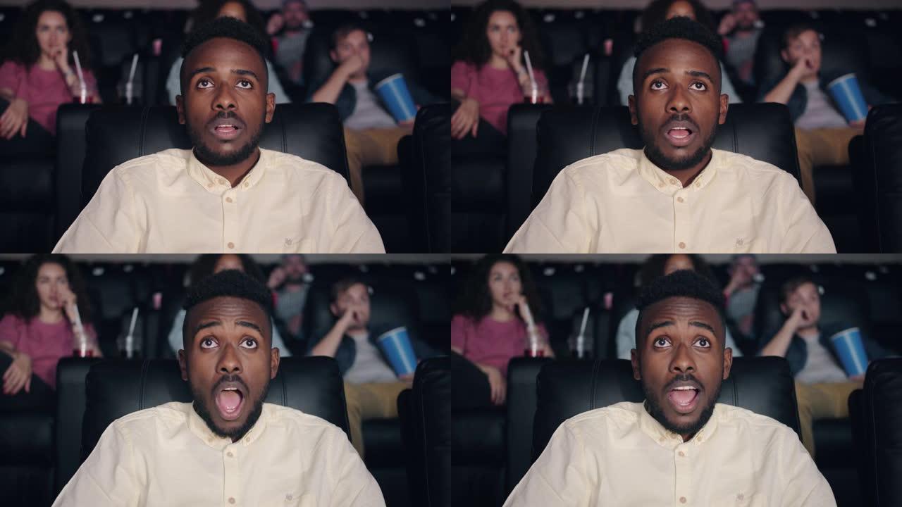 震惊的非裔美国人张开嘴在电影院看电影