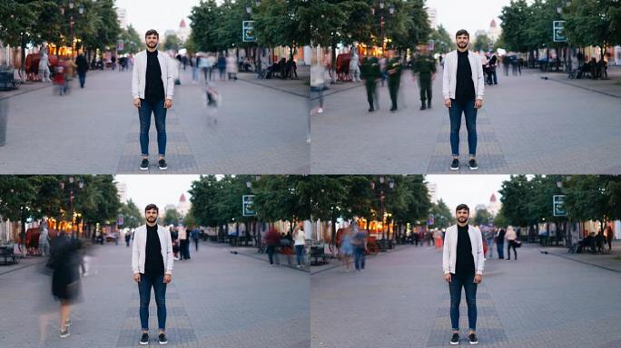 大胡子的年轻人在大城市的街道上站着，看着相机，然后在人们迅速走动时向后移动。