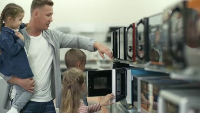 男人和三个孩子在商店里选择微波炉
