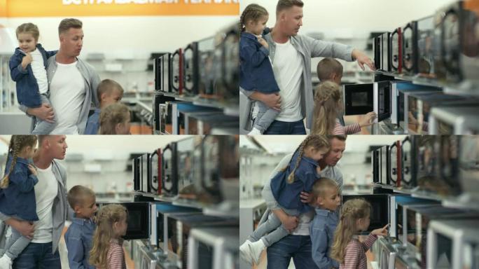 男人和三个孩子在商店里选择微波炉