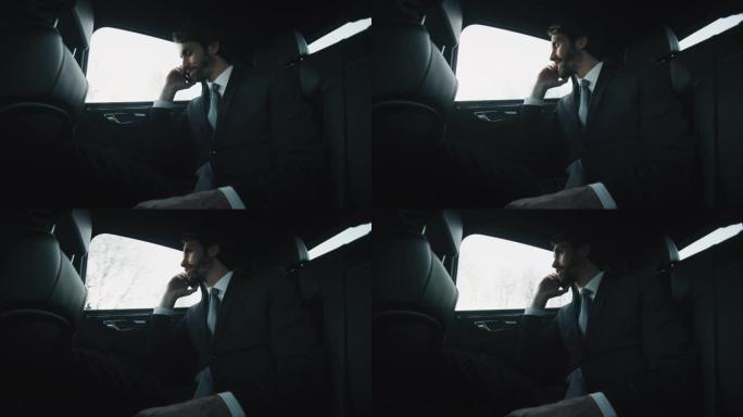 英俊的商人在一辆现代汽车旅行期间用手机打电话的慢动作与一个司机在城市中心的白天