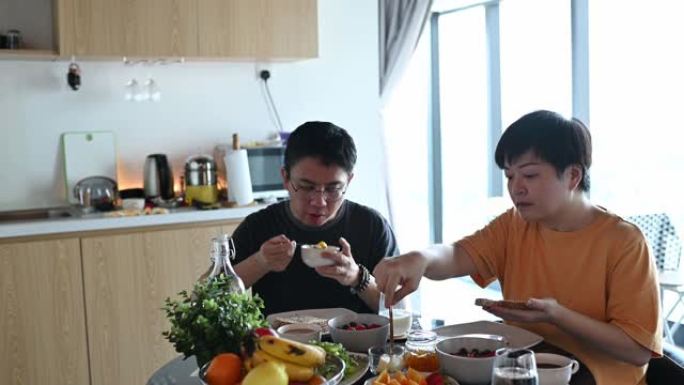 一对亚洲华裔中年夫妇早上在家享用早餐