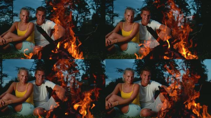 慢动作: 微笑的女人和男人坐在篝火旁，陷入沉思。