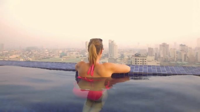 特写: 女性游客从屋顶游泳池观察越南的城市。